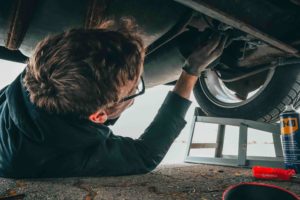 Mechanic lying under a car inspecting the underbody
